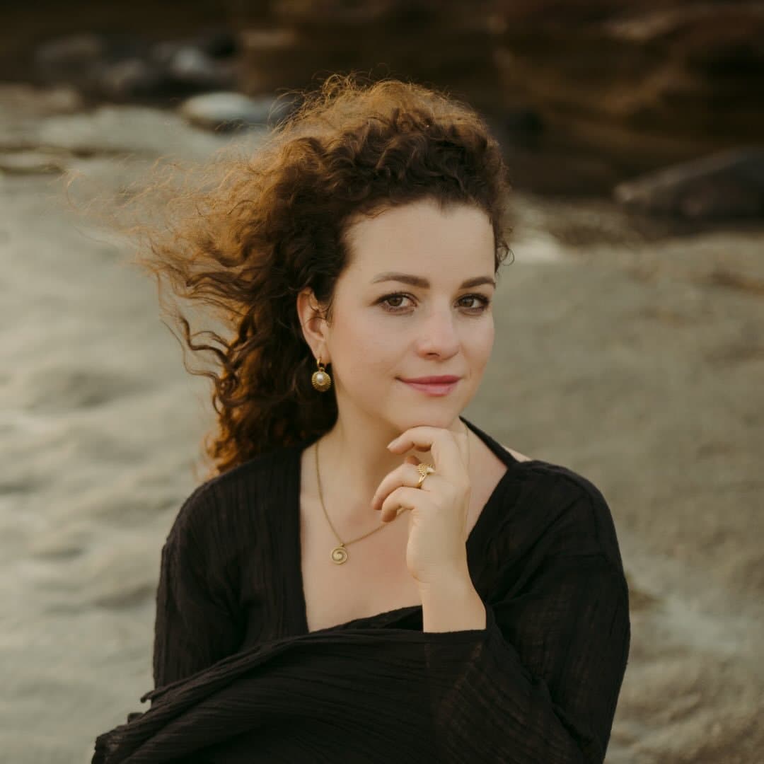 Mona Diesmann am Meer, mit lockigem Haar und einem schwarzen Oberteil